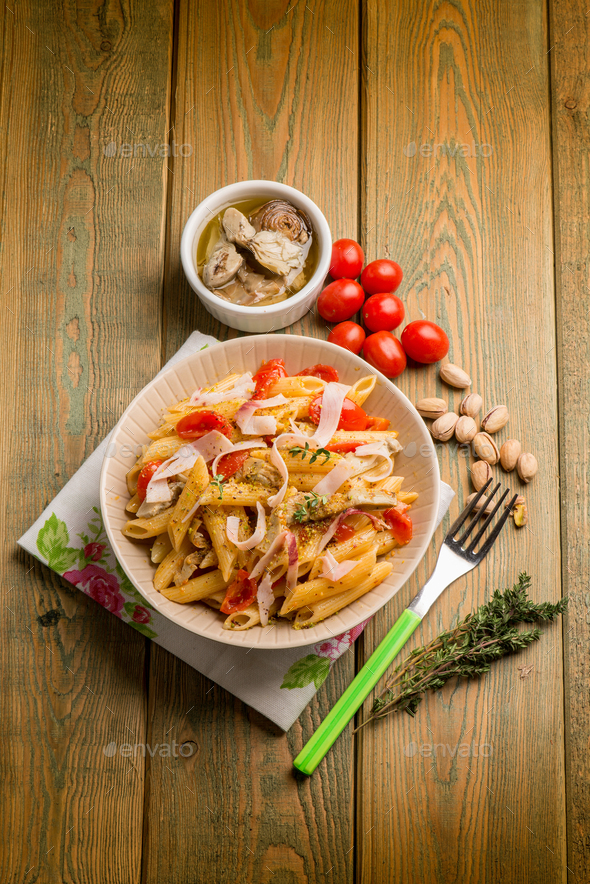 pasta with swordfish ham artichoke tomatoes and pistachio nuts Stock Photo by